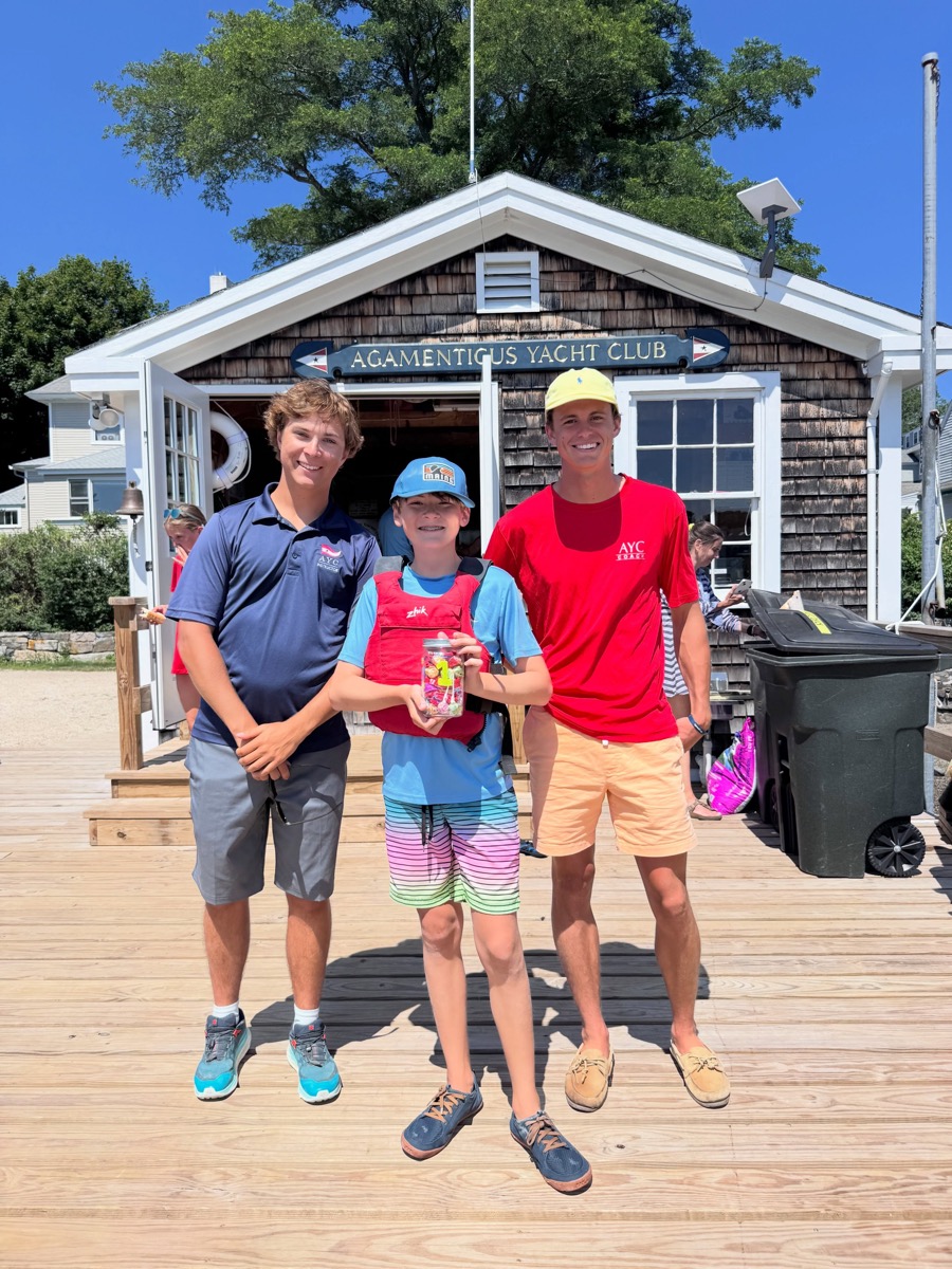 A young Opti sailor and two AYC staff members celebrating outside the clubhouse