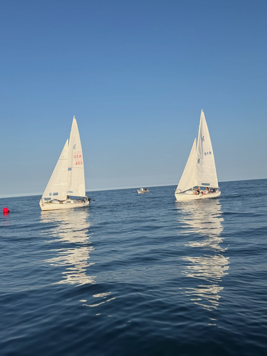 Two AYC J/22 sailboats racing on calm blue water